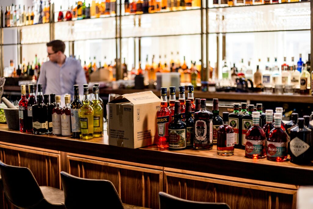 Liquor bottles are being stocked by a bartender at a bar where a wholesaler likely helped distillers distribute spirits.